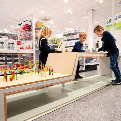 Kinderen spelen in een kleurrijke kinderhoek in een HEMA-winkel, ontworpen door IKC met houten speelelementen en educatief speelgoed.